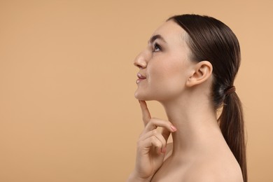 Photo of Beautiful woman touching her chin on beige background. Space for text