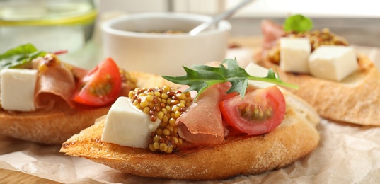 Image of Delicious bruschettas with prosciutto and cheese served on board, closeup. Banner design 