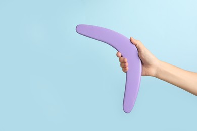 Photo of Woman holding boomerang on light blue background, closeup. Space for text