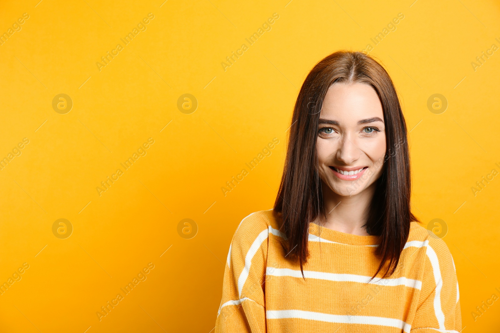 Photo of Portrait of pretty young woman with gorgeous chestnut hair and charming smile on yellow background, space for text