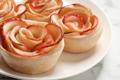 Photo of Freshly baked apple roses on white table, closeup. Beautiful dessert
