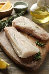 Photo of Fresh raw cod fillets, spices and lemon on wooden table, closeup