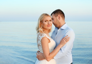 Photo of Wedding couple. Groom hugging bride on beach