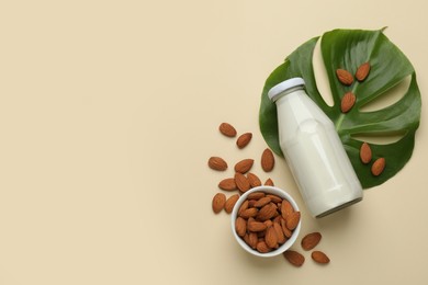 Photo of Bottle of vegan milk and almond nuts on beige background, flat lay. Space for text