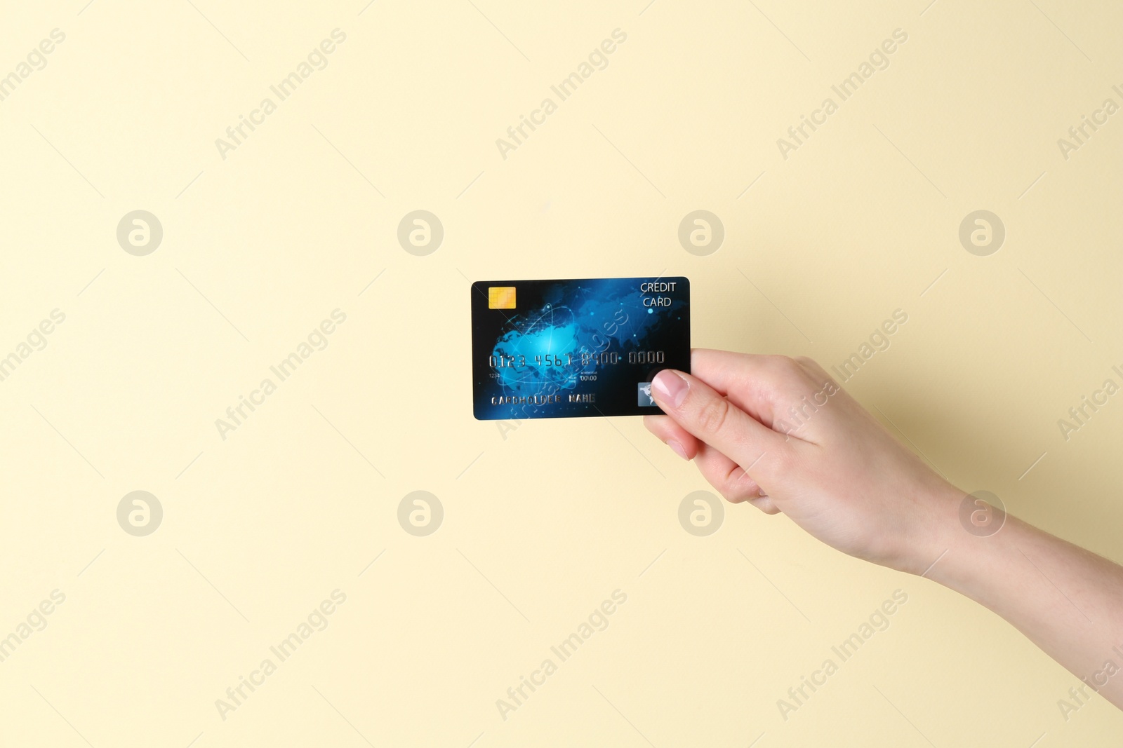 Photo of Woman holding credit card on pale yellow background, closeup