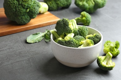 Photo of Bowl of fresh broccoli on grey table. Space for text