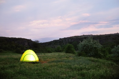 Photo of Small camping tent glowing in twilight, outdoors