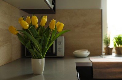 Photo of Bouquet of beautiful yellow tulips on countertop in kitchen, space for text