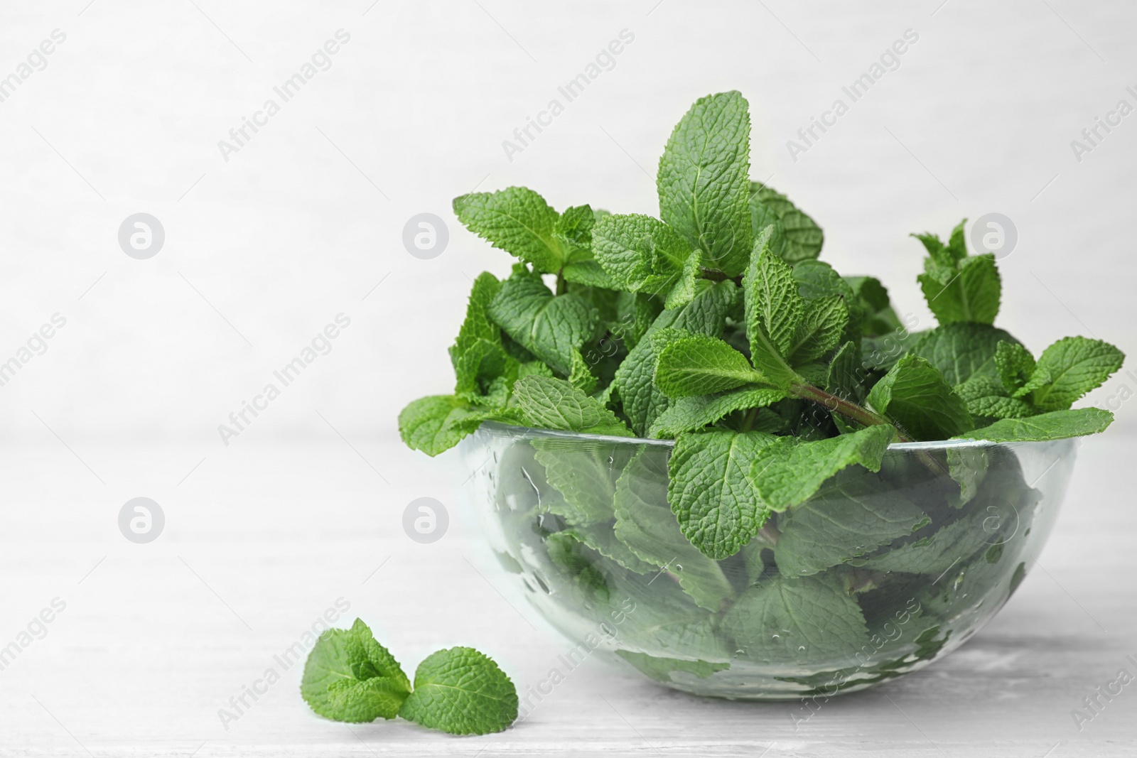 Photo of Glass bowl with fresh green mint on table. Space for text