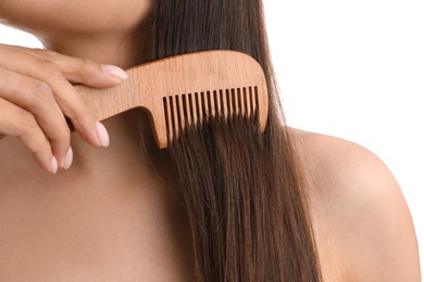 Young woman with wooden hair comb on white background, closeup