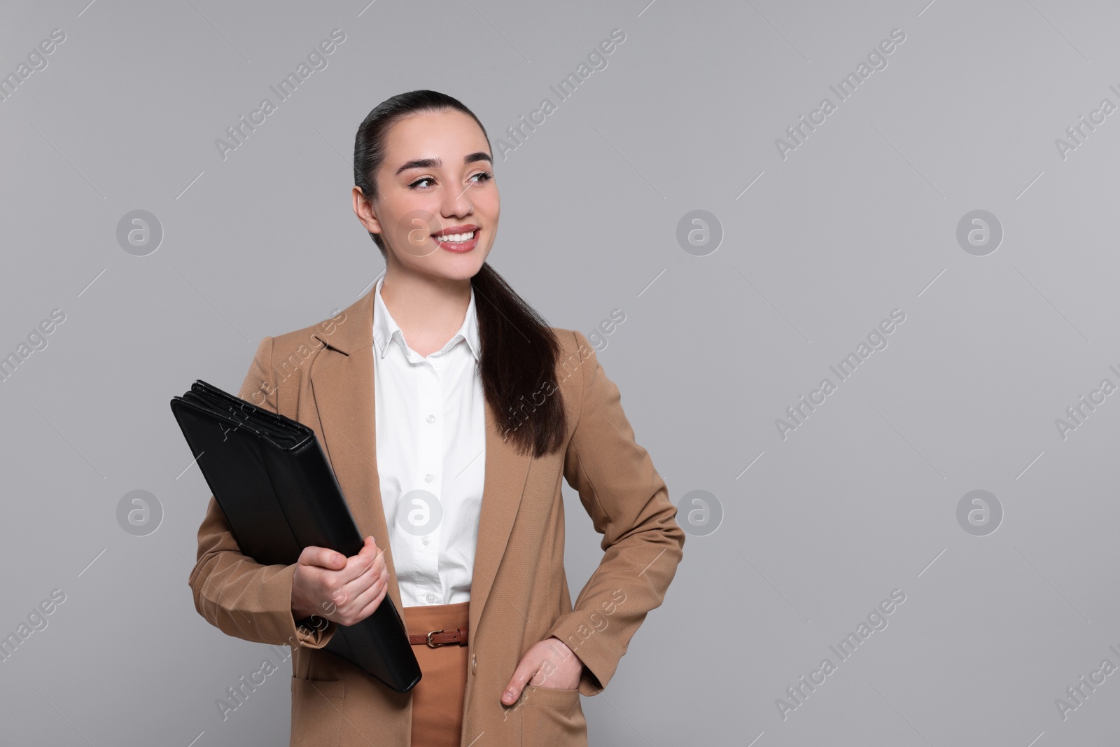 Photo of Happy real estate agent with leather portfolio on grey background. Space for text