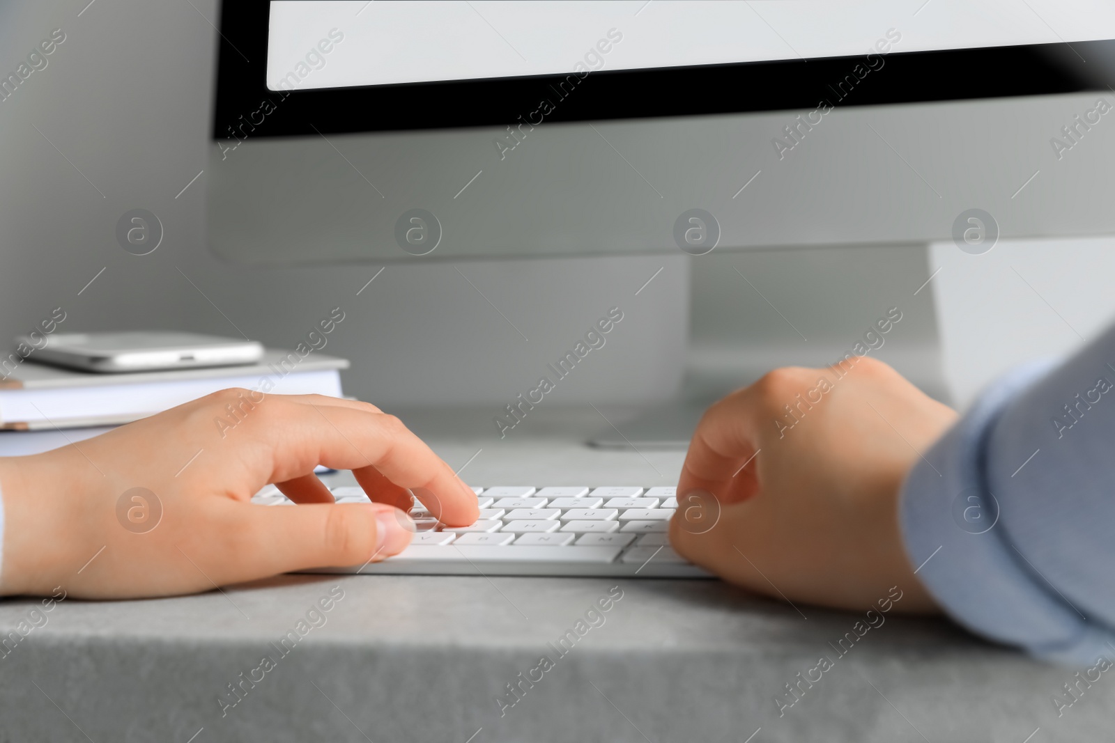 Photo of Woman working on modern computer at grey table, closeup