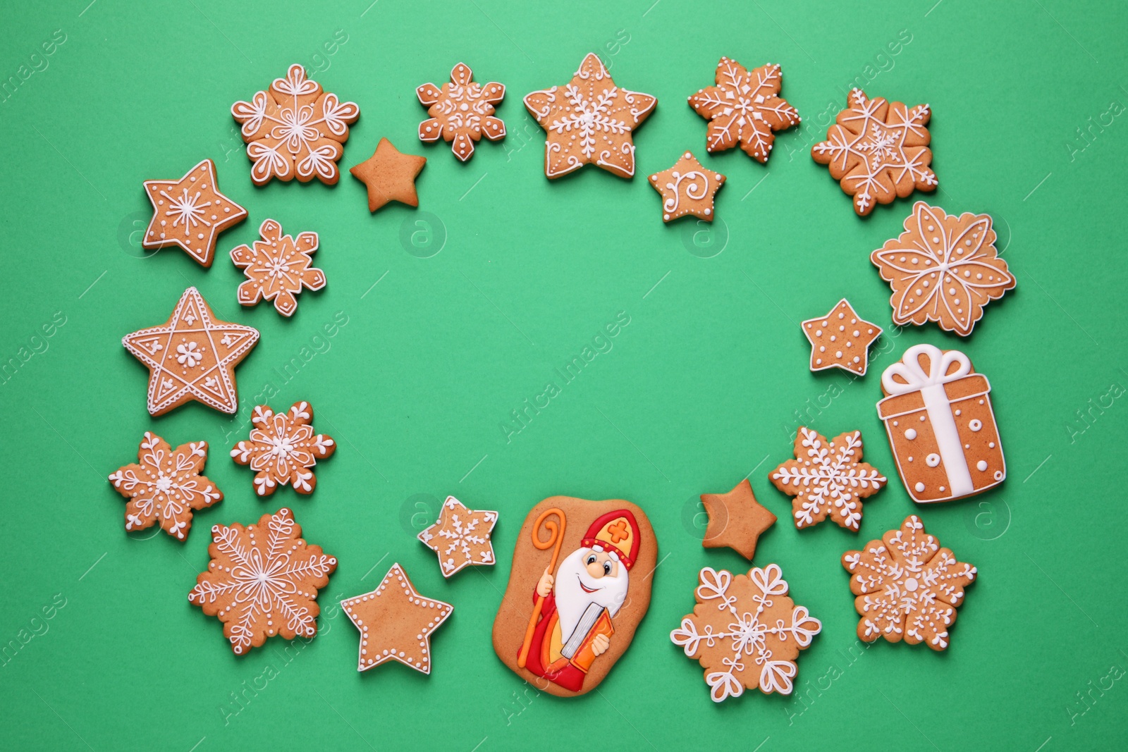 Photo of Frame of tasty gingerbread cookies on green background, flat lay with space for text. St. Nicholas Day celebration