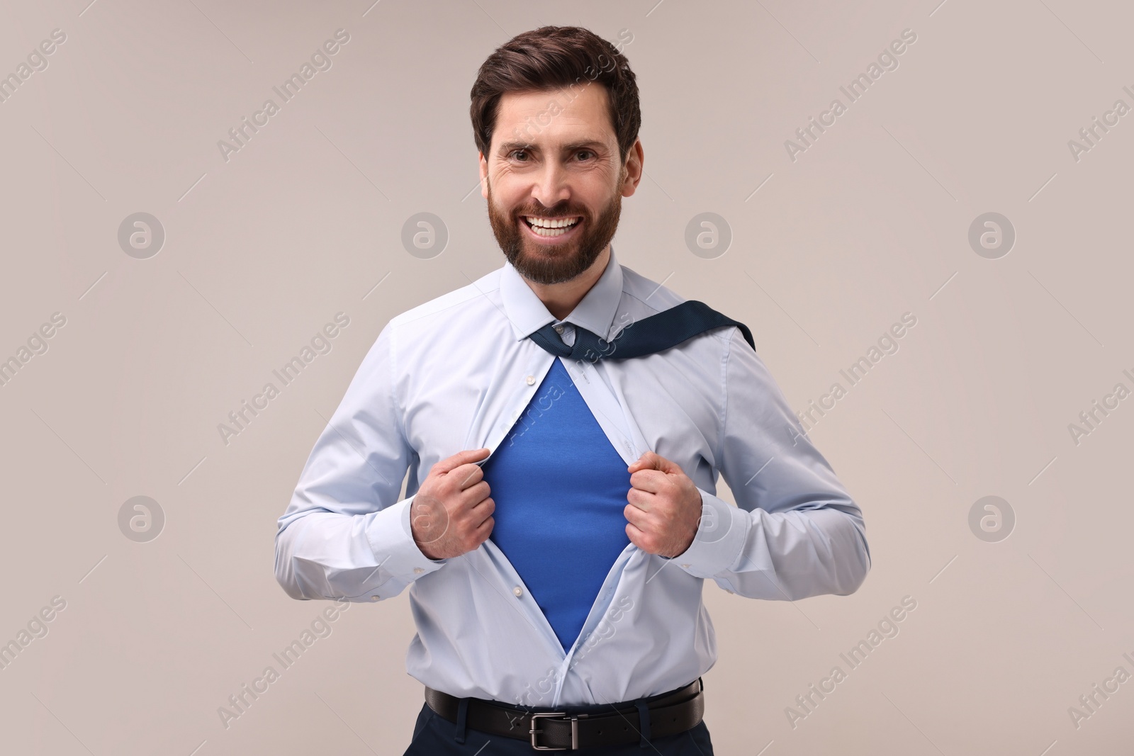 Photo of Happy businessman wearing superhero costume under suit on beige background