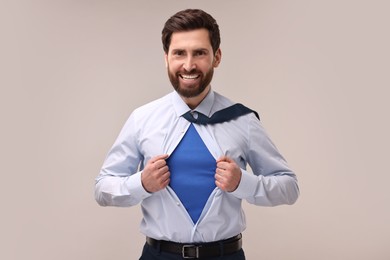 Photo of Happy businessman wearing superhero costume under suit on beige background