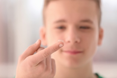 Teenage boy with contact lens on blurred background