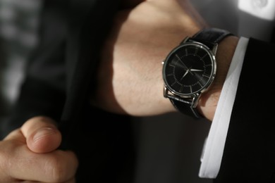 Photo of Businessman with luxury wrist watch on blurred background, closeup