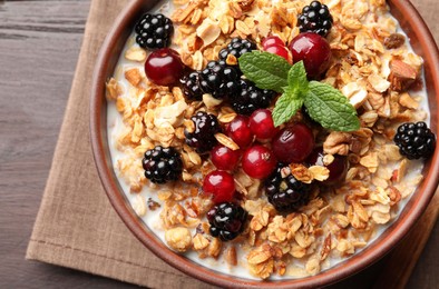 Photo of Bowl of muesli served with berries and milk on wooden table, top view