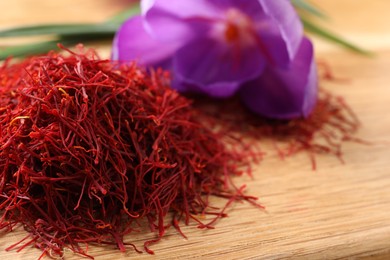 Photo of Dried saffron and crocus flower on wooden board, closeup