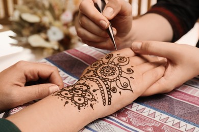 Photo of Master making henna tattoo on hand, closeup. Traditional mehndi