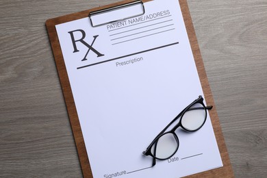 Clipboard with medical prescription form and glasses on wooden table, top view