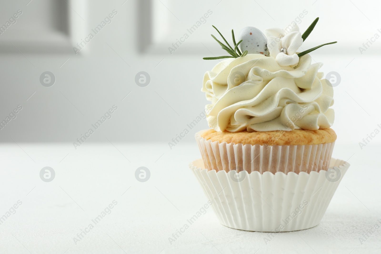 Photo of Tasty Easter cupcake with vanilla cream on white table, space for text