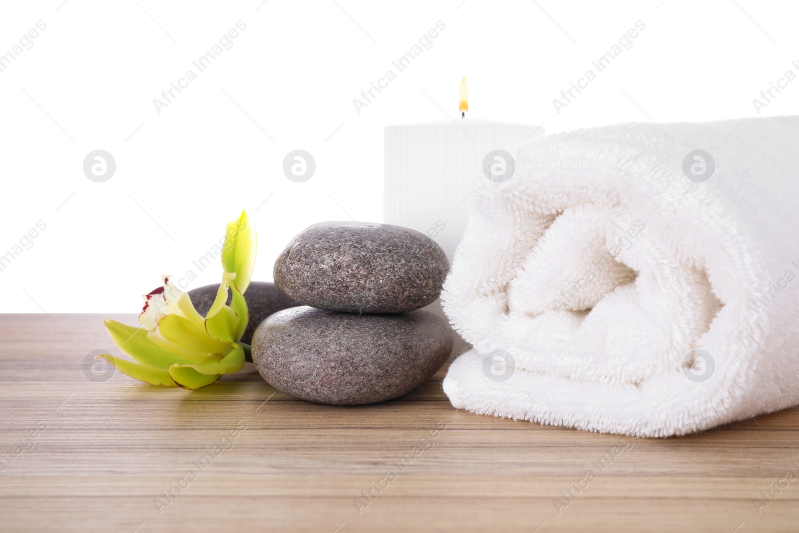 Photo of Fresh towel, spa stones and exotic flower on wooden table against white background