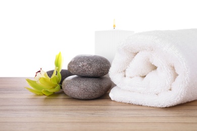 Fresh towel, spa stones and exotic flower on wooden table against white background