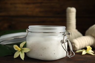 Photo of Jar of salt scrub and orchid flower on wooden table