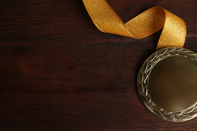 Photo of Gold medal with ribbon on wooden background, flat lay. Space for design