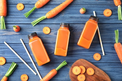 Photo of Bottles with carrot juice and fresh vegetable on wooden table, top view