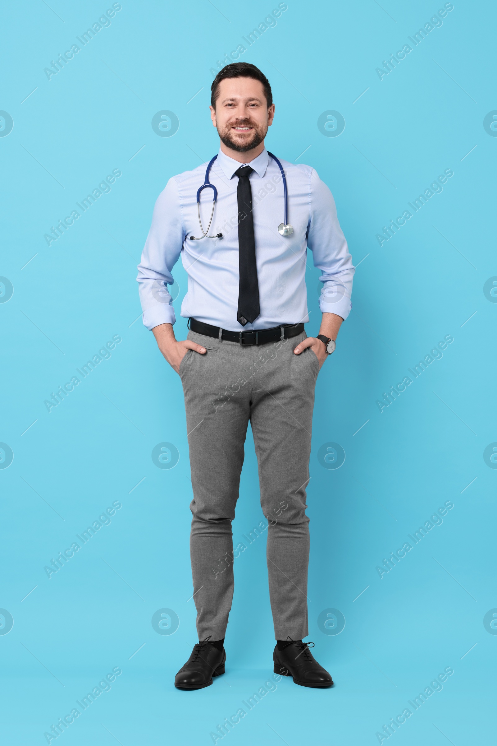 Photo of Full length portrait of smiling doctor on light blue background