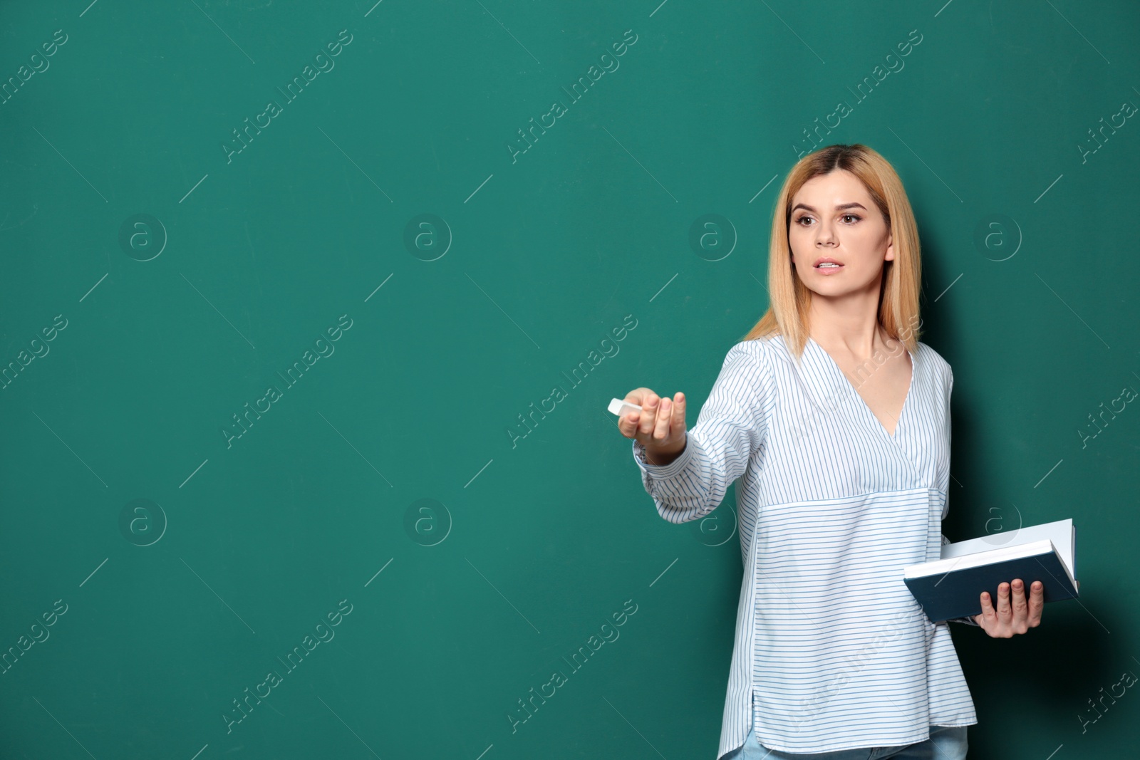 Photo of Beautiful teacher with book near chalkboard, space for text