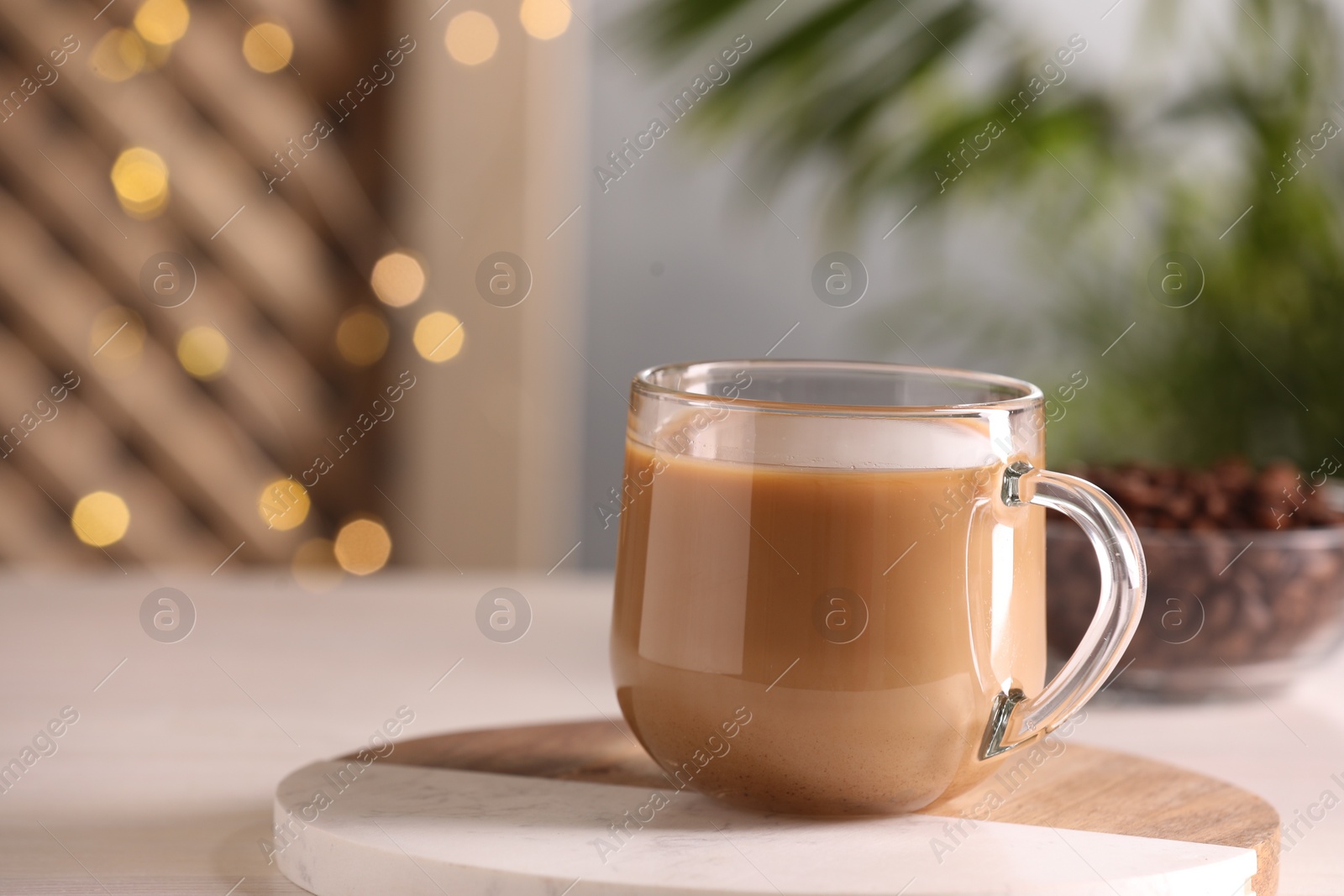 Photo of Delicious coffee with milk in cup on white table, closeup. Space for text