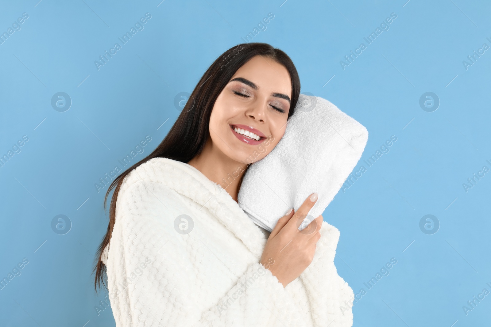 Photo of Young woman wiping face with towel on light blue background