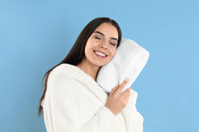 Photo of Young woman wiping face with towel on light blue background