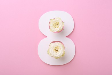 Photo of Paper number 8 and beautiful rose flowers on pink background, top view