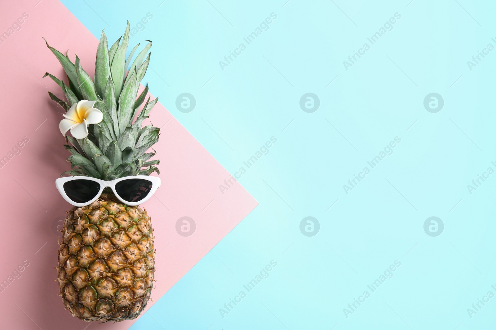 Photo of Top view of pineapple with sunglasses and flower on color background, space for text. Creative concept