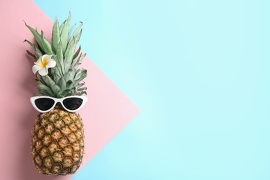 Photo of Top view of pineapple with sunglasses and flower on color background, space for text. Creative concept