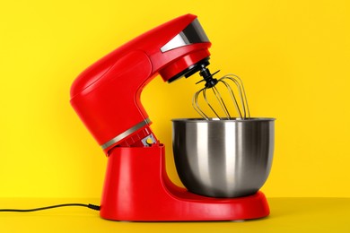 Photo of Modern red stand mixer on yellow background