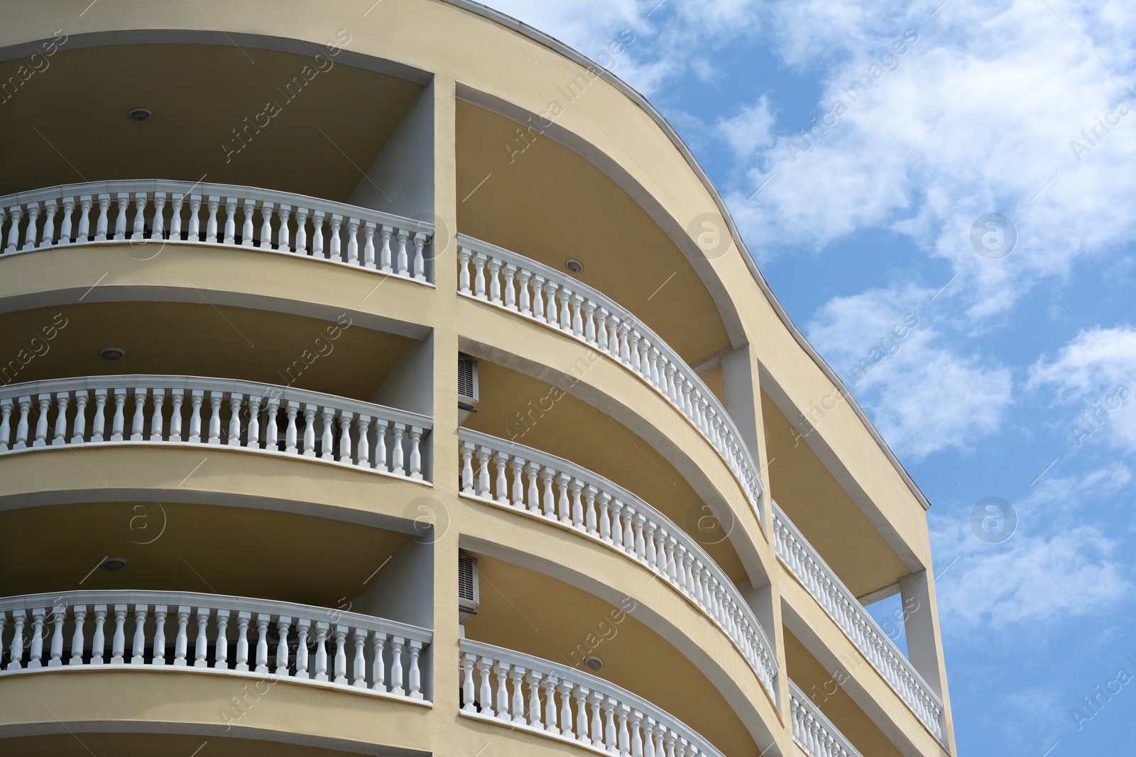 Photo of Exterior of beautiful building with balconies against blue sky, low angle view