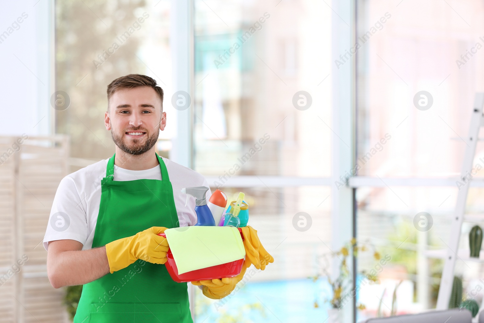 Photo of Man in uniform with cleaning supplies indoors