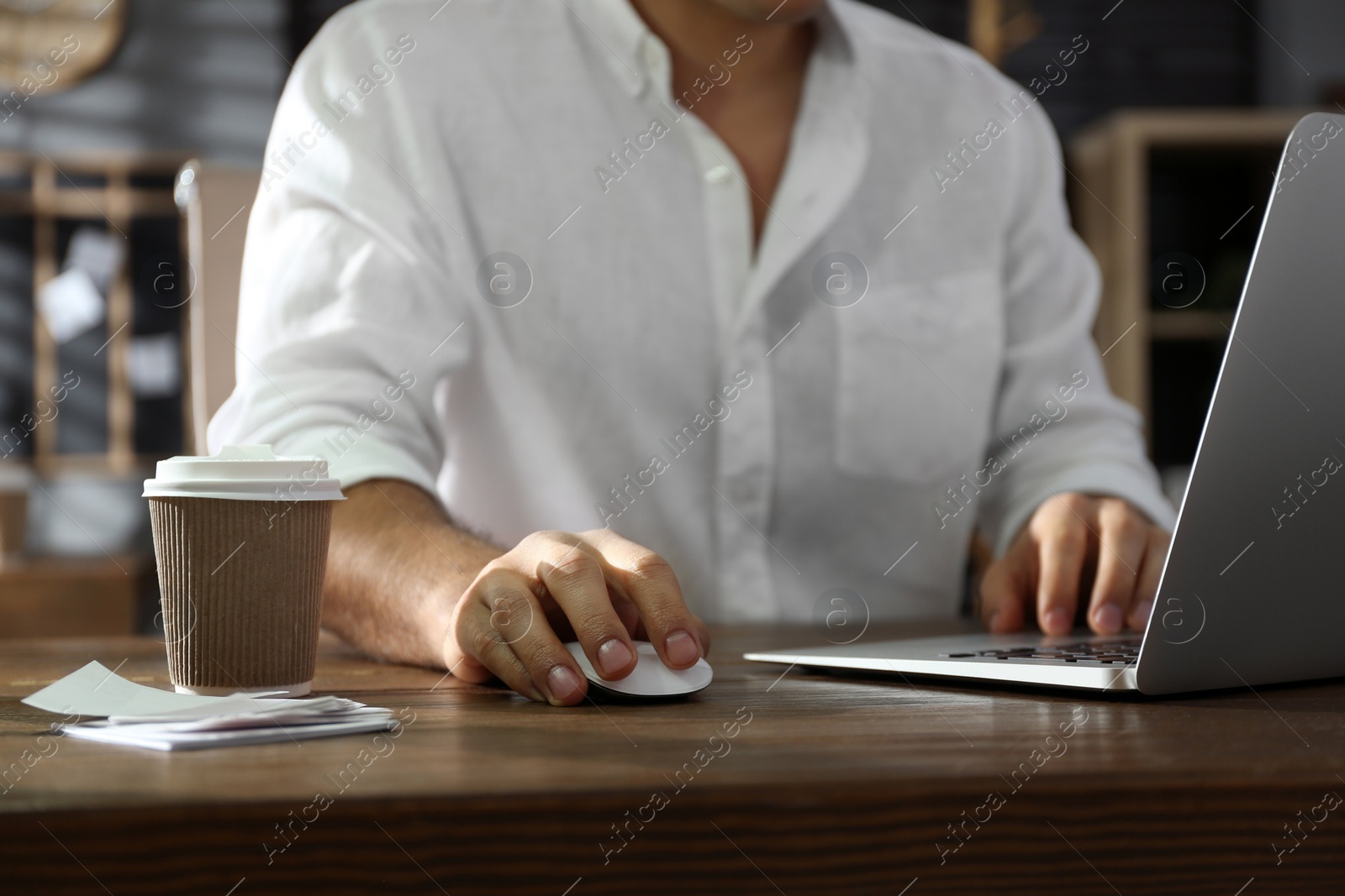 Photo of Freelancer working on laptop at table indoors, closeup