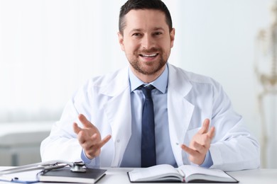 Portrait of smiling doctor at table in clinic