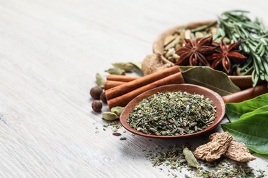 Different natural spices and herbs on light wooden table, closeup. Space for text