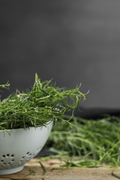 Photo of Fresh tarragon sprigs on wooden table, closeup. Space for text