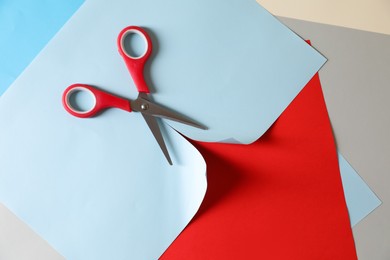 Photo of Red scissors and color paper on white background, flat lay