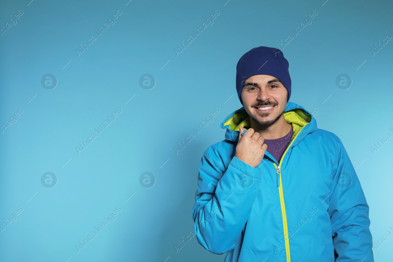 Photo of Young man wearing warm clothes on color background, space for text. Ready for winter vacation