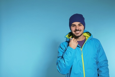 Young man wearing warm clothes on color background, space for text. Ready for winter vacation