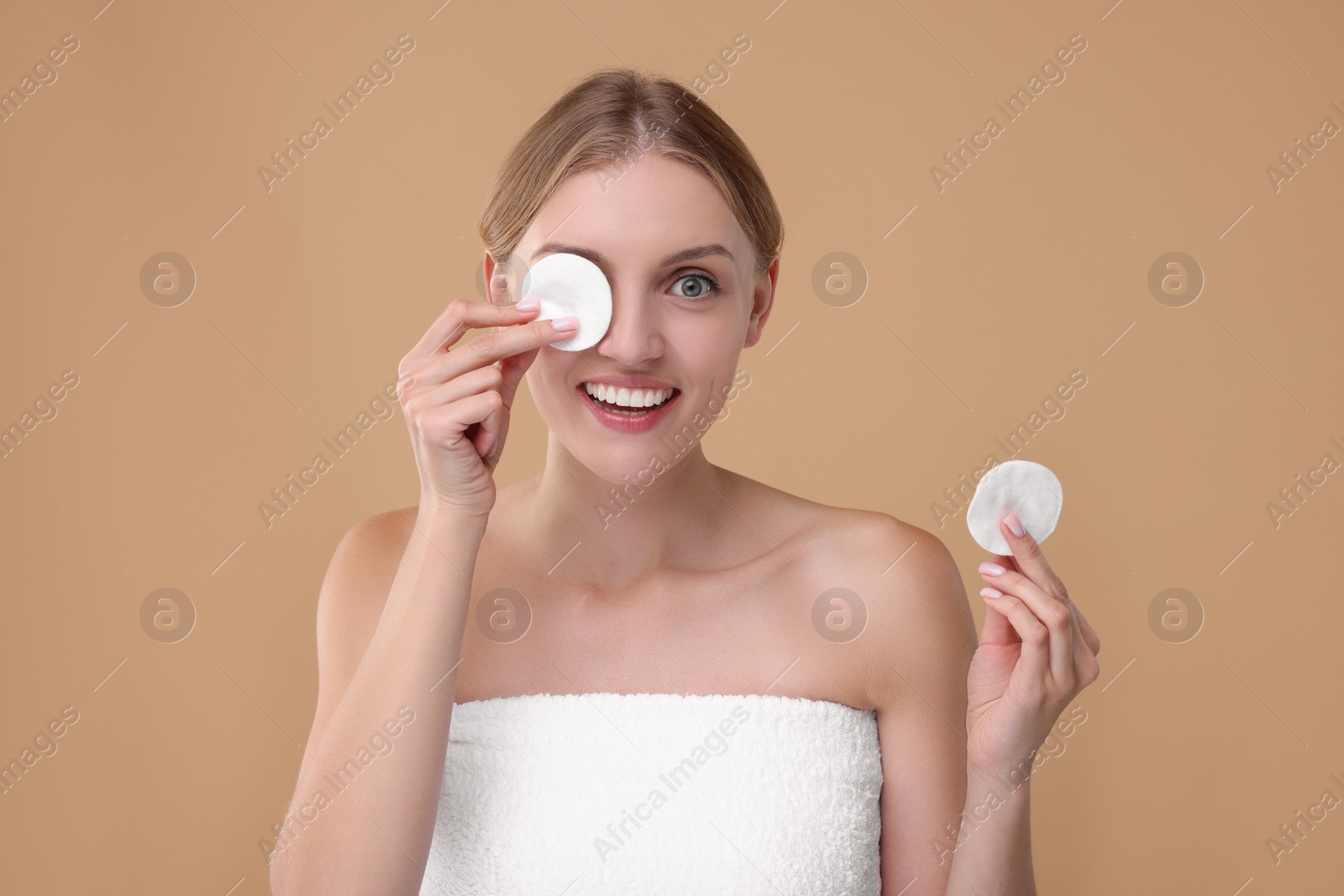 Photo of Young woman with cotton pad on beige background